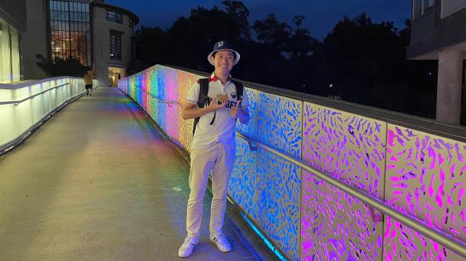 一個人站在一座彩虹燈光裝飾的橋上